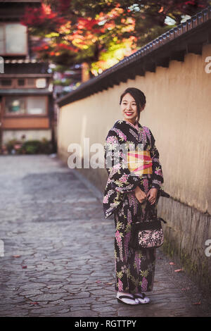 KANAZAWA, Japan - 28. NOVEMBER: japanische Mädchen im Kimono im Viertel Nagamachi Samurai posieren. Der Bereich Konserven samurai Residenzen, irdenen Wände, ent Stockfoto