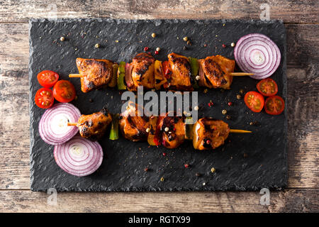 Hühnchen Shish Kebab mit Gemüse auf hölzernen Tisch. Ansicht von oben. Stockfoto