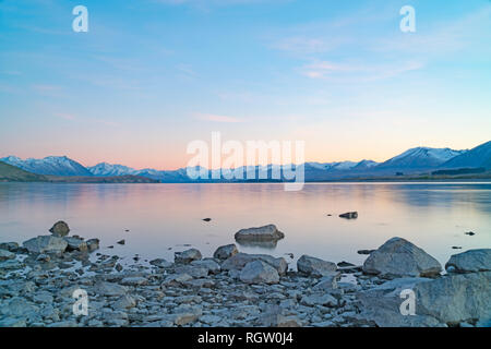 Malerische Wirkung Lake Tekapo sunsise über felsige Küste und niedrigem Wasserstand der Ruhe ruhige See Stockfoto