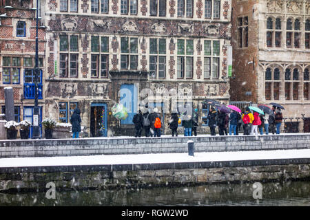 Geführte Tour mit Touristen, die die Stadt Gent bei Schnee Dusche im Winter, Ostflandern, Belgien Stockfoto