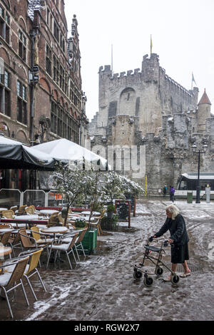 Ältere Frau mit rollator/Rollator zu Fuß auf glatter Fahrbahn während Schneeregen/Schnee Dusche im Winter in der Stadt Gent, Flandern, Belgien Stockfoto