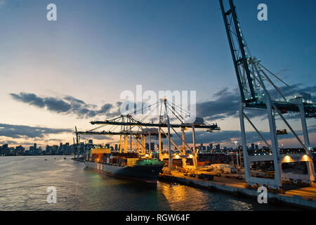 Miami, USA - 01. März 2016: Frachtschiff und Kräne im Hafen am Abendhimmel. Maritime Container Hafen oder Terminal. Liefer- fracht- und Merchandise. Wasser Transport und Verkehr Konzept Stockfoto