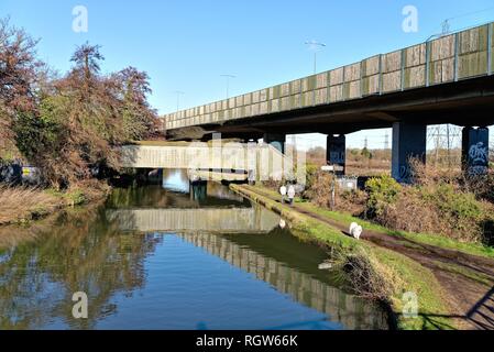 Der Kreuzung des Flusses Wey und der Basingstoke Canal an New Haw mit Paar mit Hund im Winter auf dem Leinpfad, Surrey, England, Großbritannien Stockfoto
