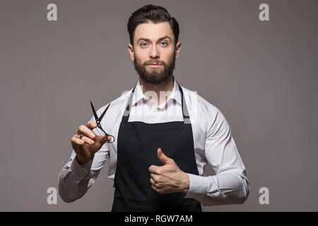 Portrait von Friseur holding Ausrüstungen in der Hand, an der Kamera suchen, auf weißem Hintergrund Stockfoto