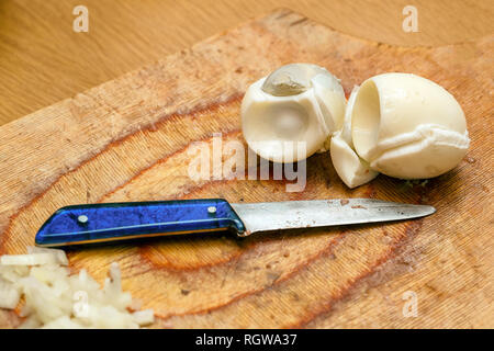 Gekochte Eier und ein Messer auf dem Schneidebrett in der Küche Stockfoto