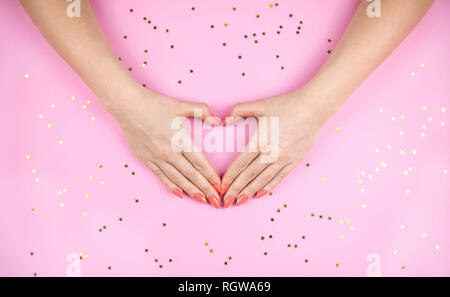 Woman's Hand mit Coral Maniküre Herz. Stockfoto