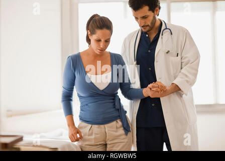 Männlicher Arzt helfen Patienten, hält ihre Hand und hilft ihr zu gehen. Stockfoto