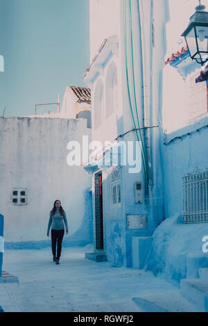 Junge Touristenfrau, die auf der weißen Straße in Chefchaouen, Marokko, läuft Stockfoto