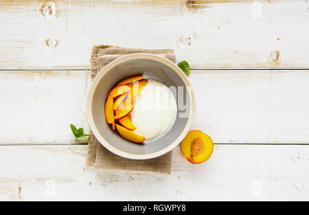 Frische Pfirsiche und griechischer Joghurt in Frühstück Schüssel flach. Gesunde Ernährung Konzept. Stockfoto
