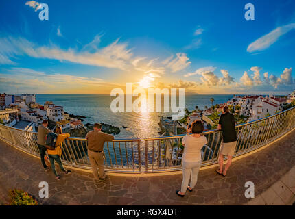 Gruppe von Menschen beobachten Sonnenuntergang im Atlantischen Ozean an der Küste von Puerto de Santiago auf Teneriffa, Spanien Stockfoto