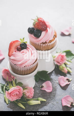 Cupcakes mit auf Porzellan steht mit rosa Blüten auf einem weißen Hintergrund. Feder dessert Konzept mit Kopie Raum Stockfoto