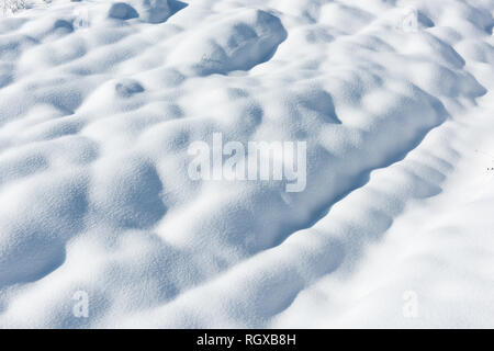 Große Schneeverwehungen auf einem schneebedeckten Feld Stockfoto