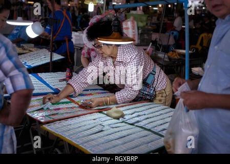 Thailand Lotterie. Menschen kaufen Lotterie von einer weiblichen Lottery ticket Anbieter. Südostasien Stockfoto