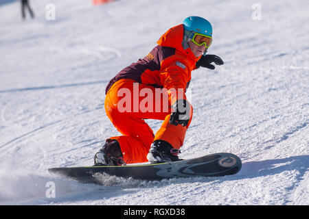 Ein männlicher Snowboarder schnitzt eine Umdrehung auf der Piste in den Französischen Alpen Courchevel. Stockfoto