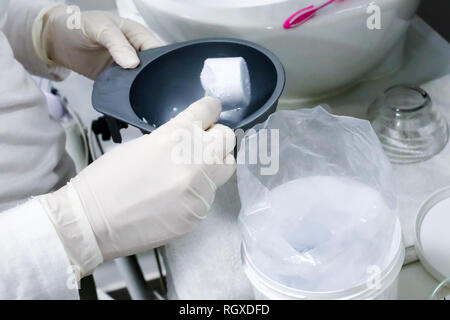 Weibliche Arbeitnehmer in weißen Handschuhen im Beauty Salon, Kaviar Peel Off Maske für die Gesichtspflege Stockfoto