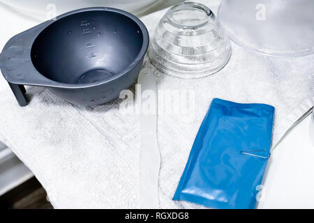 Leere Schüssel aus Kunststoff und Glas, Kunststoff und Kunststoff blau Verpackung auf weißem Handtuch im Beauty Salon, Stockfoto