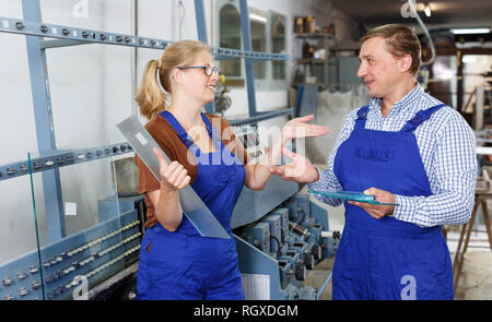 Erwachsene Frau und ihr männlicher Kollege arbeitet in der gläsernen Werkstatt Stockfoto