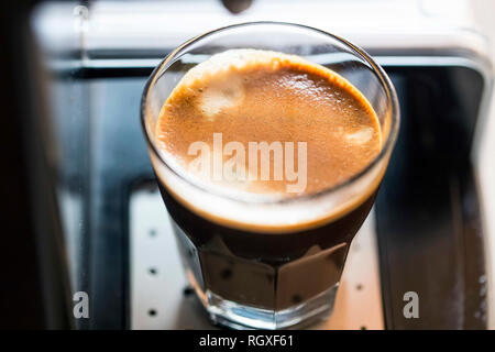 Doppelter Espresso Tasse wird frisch auf Kaffee maschine Nahaufnahme mit cremigem Milchschaum, warmes Braun Aroma Kaffee Tasse Stockfoto