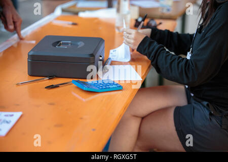 Mädchen, dass Konten und Kleine Metall Kasse und Taschenrechner auf einen hölzernen Tisch. Stockfoto