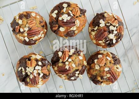 Frisch gebackene Banane Haferflocken Pecan und Schokolade Muffins auf Kühlung rack Schuß von Overhead bei Tageslicht. Gesunde und nahrhafte Zwischenmahlzeit. Stockfoto