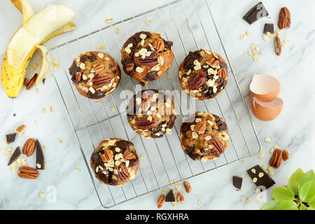 Frisch gebackene Banane Haferflocken Pecan und Schokolade Muffins auf Kühlung rack Schuß von Overhead bei Tageslicht. Gesunde und nahrhafte Zwischenmahlzeit. Stockfoto