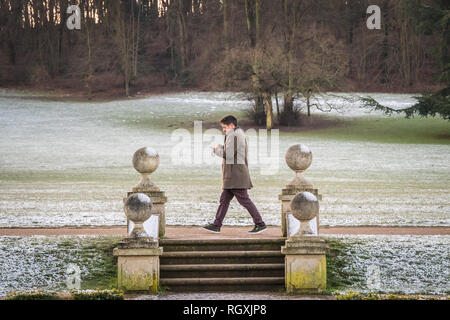 Reigate, Großbritannien - 30 Januar, 2019 - ein Mann Spaziergänge durch verschneite Felder der Priory Park in Redhill, Großbritannien, an einem kalten Wintermorgen Stockfoto