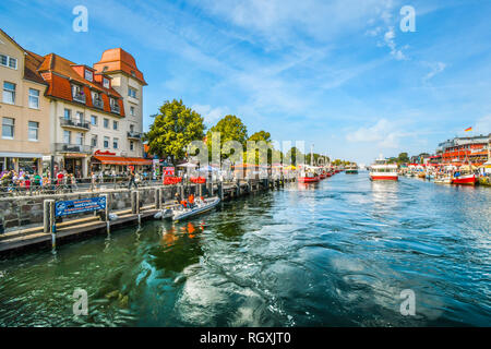 Touristen genießen die Geschäfte, Boote und Cafés auf dem Strom boardwalk Ändern in der Stadt Warnemünde, Rostock an der nördlichen Küste von Deutschland Stockfoto