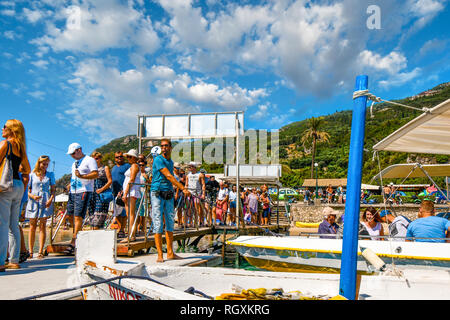 Korfu, Griechenland - 20. September 2018: eine Tour boot Führer hält die Boote im Dock als Touristen Line up auf Palaiokastritsa Strand auf der Insel Korfu Stockfoto