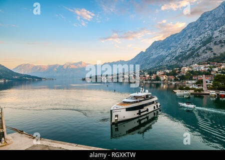 Kotor, Montenegro: eine Luxusyacht zieht in den Hafen am frühen Morgen die Sonne über die Berge und den smaragdgrünen Gewässern der Bucht von Kotor Stockfoto