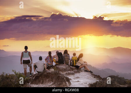 Große Gruppe von Freunden steht auf einem Berg und blickt auf den wunderschönen Sonnenuntergang. Reisen mit Freunden Konzept Stockfoto