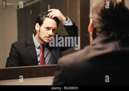 Besorgt Hispanic Mann auf Haarlinie in Büro sanitäre Einrichtungen Stockfoto