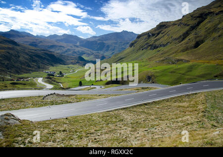 Mountain Road mit vielen Kurven mit blauem Himmel und Wolken in Graubünden, Schweiz. Stockfoto