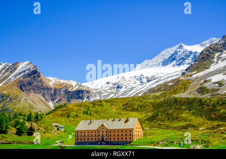 Großes Gebäude mit schneebedeckten Berge und blauer Himmel in Simplonpass, im Sommer, im Wallis, Schweiz. Stockfoto