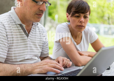 Mann und Frau im Freien Arbeiten auf einem Laptop. Stockfoto