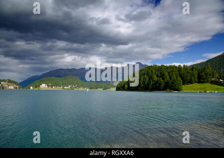 St. Moritz, den See und die Berge und grüne Bäume mit grauen Wolken an einem sonnigen Tag in der Schweiz. Stockfoto