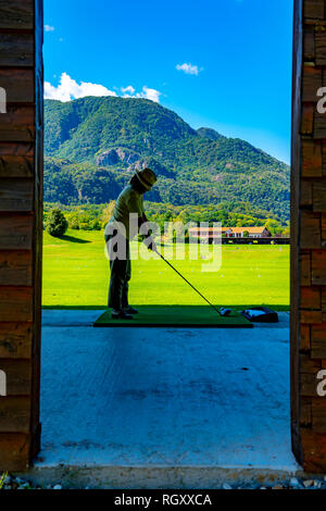 Golfspieler auf der Driving Range mit Blick auf die Berge in der Schweiz. Stockfoto