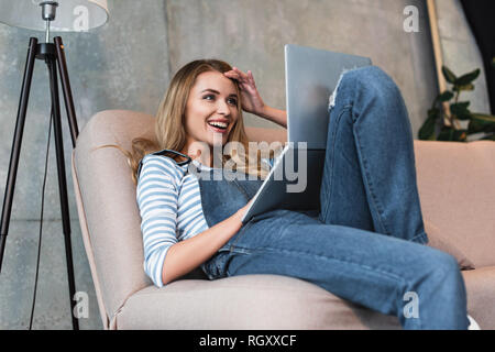 Junge Mädchen lächelnd und überrascht auf Monitor des Laptops Stockfoto