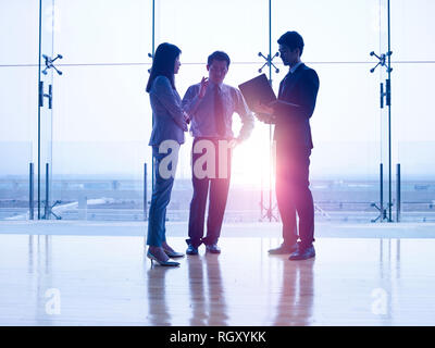 Die Silhouetten der drei asiatischen Führungskräfte stehen vor Windows Diskussion von mit Laptop Computer. Stockfoto