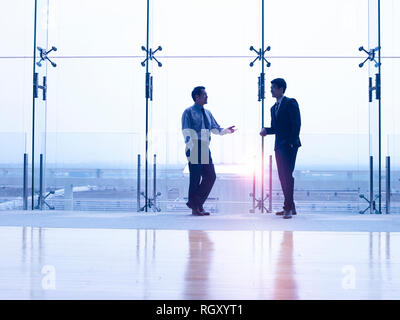 Zwei asiatischen Führungskräfte stehen durch die Windows chat sprechen Stockfoto