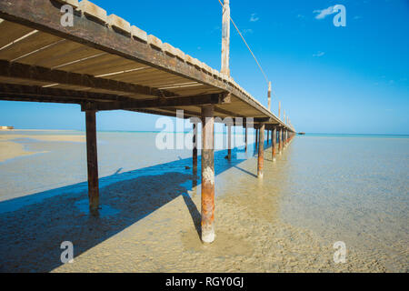 Hölzerne Pier Anlegestelle ausgehend vom tropischen Strand ins Meer Stockfoto