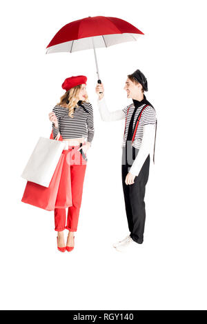 Fröhliche Frau mit Einkaufstüten und Mann mit Schirm isoliert auf weißem Stockfoto
