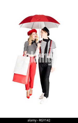 Fröhliche Frau mit Einkaufstüten an Freund suchen Beim stehen unter der Schirmherrschaft von Weiß isoliert Stockfoto
