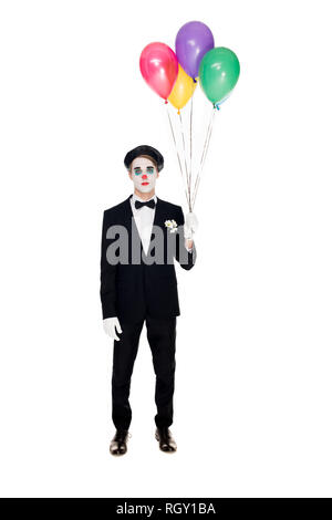 Trauriger Clown in Anzug und schwarzen Barett holding Heliumballons isoliert auf weißem Stockfoto