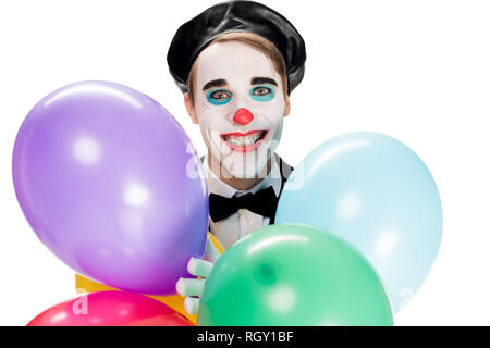 Fröhliche Clown in schwarzen Barett holding Ballons und lächelnd auf Weiß isoliert Stockfoto