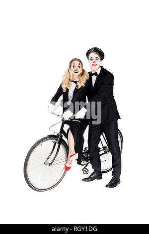 Lächelndes Paar clowns Reiten Fahrrad isoliert auf weißem Stockfoto