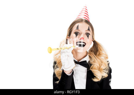 Weibliche Clown in Anzug lächelnd, während sie Geburtstag Gebläse isoliert auf weißem Stockfoto