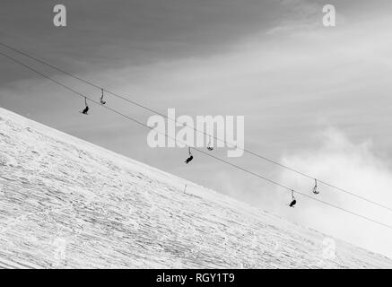 Snowy off-piste Skipiste mit Spuren von Skiern und Snowboards und Sesselbahn gegen Himmel mit Wolken. Kaukasus Berge im Winter, Georgien, Region G Stockfoto