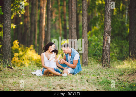 Das Thema Familie Erholung in Forest Park. Junge schöne stilvolle kaukasischen Familie mit kleinem Kind Tochter ein Jahr alt sitzen auf der gr Stockfoto