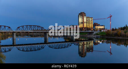 Brücke über den Fluss in der Innenstadt und der Stadt während einer lebendigen Sonnenaufgang. Saskatoon, Saskatchewan, Kanada. Stockfoto