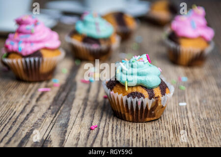 Chocolate Cupcake mit farbigen Rosa und grün Creme auf Holz Tisch Stockfoto